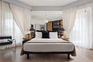 A modern bedroom with a large bed, bedside tables, a bench, and a view into another room. - Athenian Riviera Luxurious Villa & Residence (Alimos)