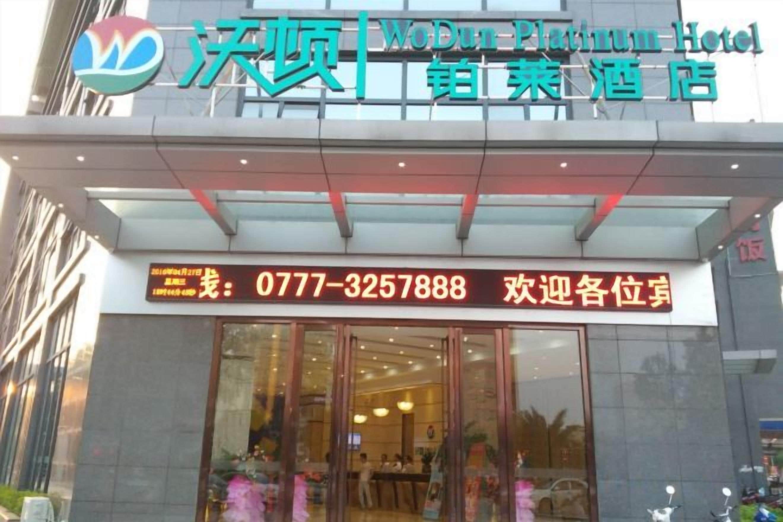 The exterior of the WoDun Platinum Hotel with a reception desk and glass doors.