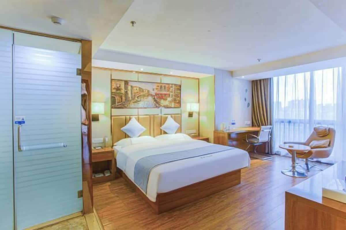 Une chambre d’hôtel avec un grand lit, un bureau, une chaise et un tableau au mur.