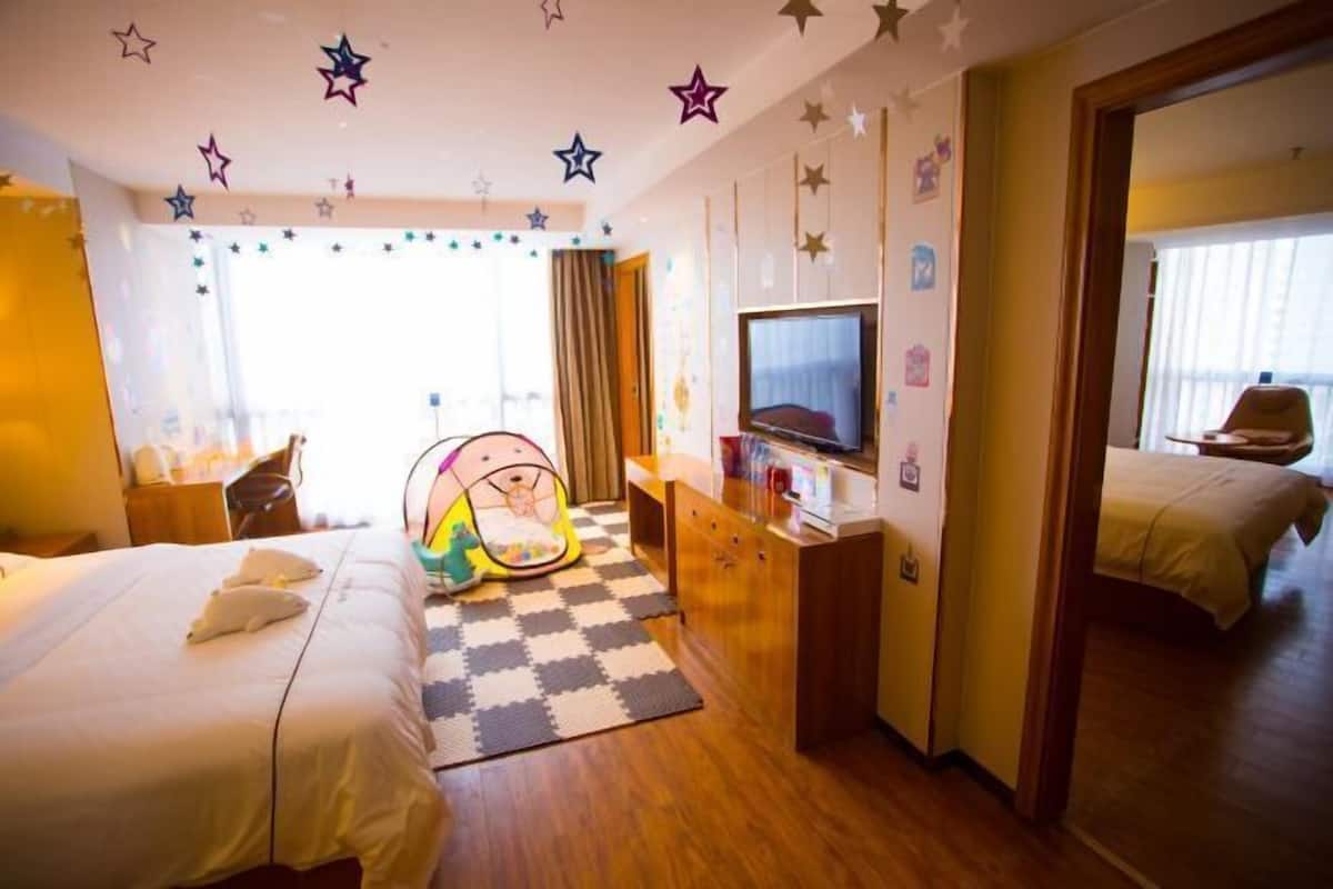 Une chambre d’hôtel avec deux lits, une télévision, un bureau, une chaise et un parc pour bébé.