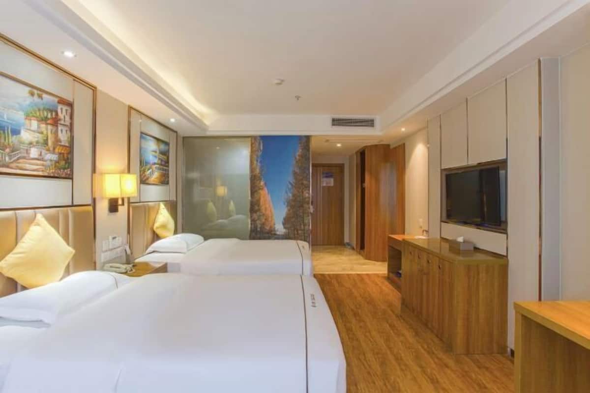 Une chambre d’hôtel avec deux lits, une télévision, une armoire en bois et une fresque murale.