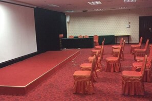Ett konferensrum med en scen, rader av stolar och ett golv täckt av matta.
