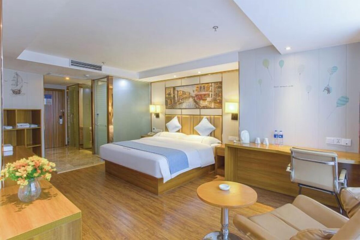Une chambre d’hôtel avec un lit, une table de chevet, une chaise et une petite table ronde.