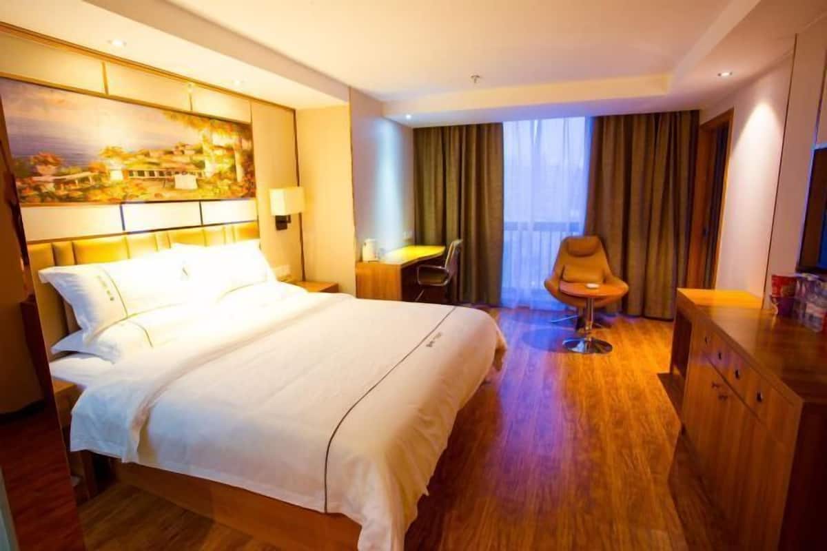 Une chambre d’hôtel avec un grand lit, un bureau, une chaise, une télévision et un tableau au mur.
