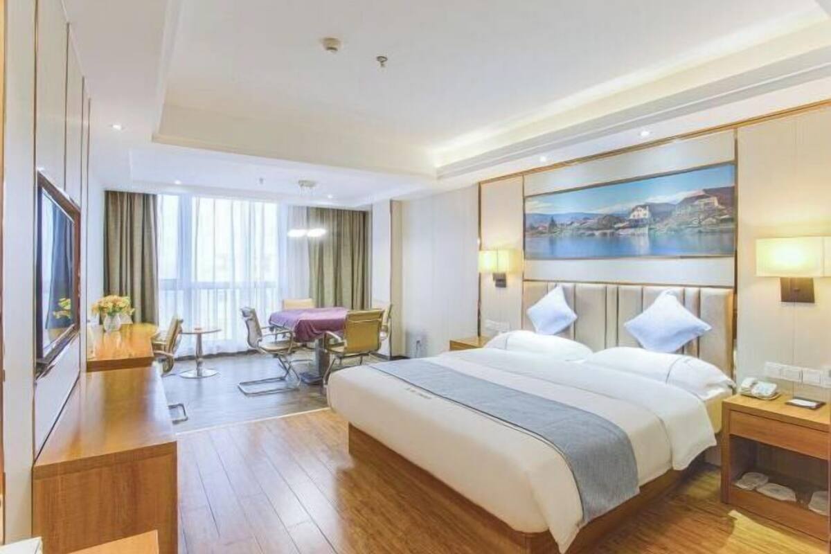 Une chambre d’hôtel avec un grand lit, un bureau, une chaise, une télévision et un tableau au mur.