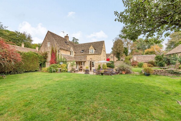 A stone house with a large garden and outdoor seating area.
