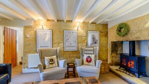 A cozy living room with a stone wall, two armchairs, a coffee table, and a fireplace. - 18th century thatched Cotswold holiday cottage in Broadway - Orchard Cottage, Broadway (Broadway)