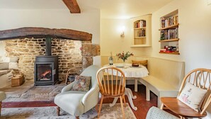 A cozy living room with a stone fireplace, wooden furniture, and bookshelves. - A delightful two bedroom Cotwold holiday cottage with garden - Cosy Corner (Moreton-in-Marsh)
