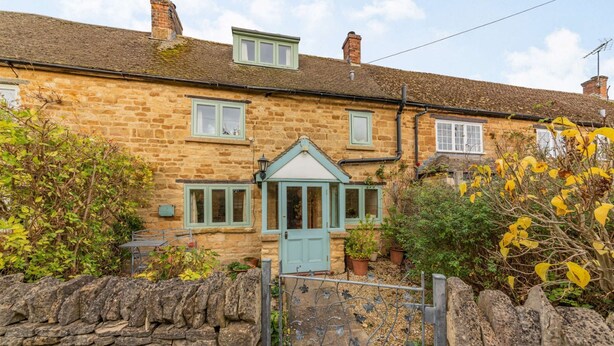A stone house with a blue door, a small porch, and a stone wall in front. - A delightful two bedroom Cotwold holiday cottage with garden - Cosy Corner (Moreton-in-Marsh)