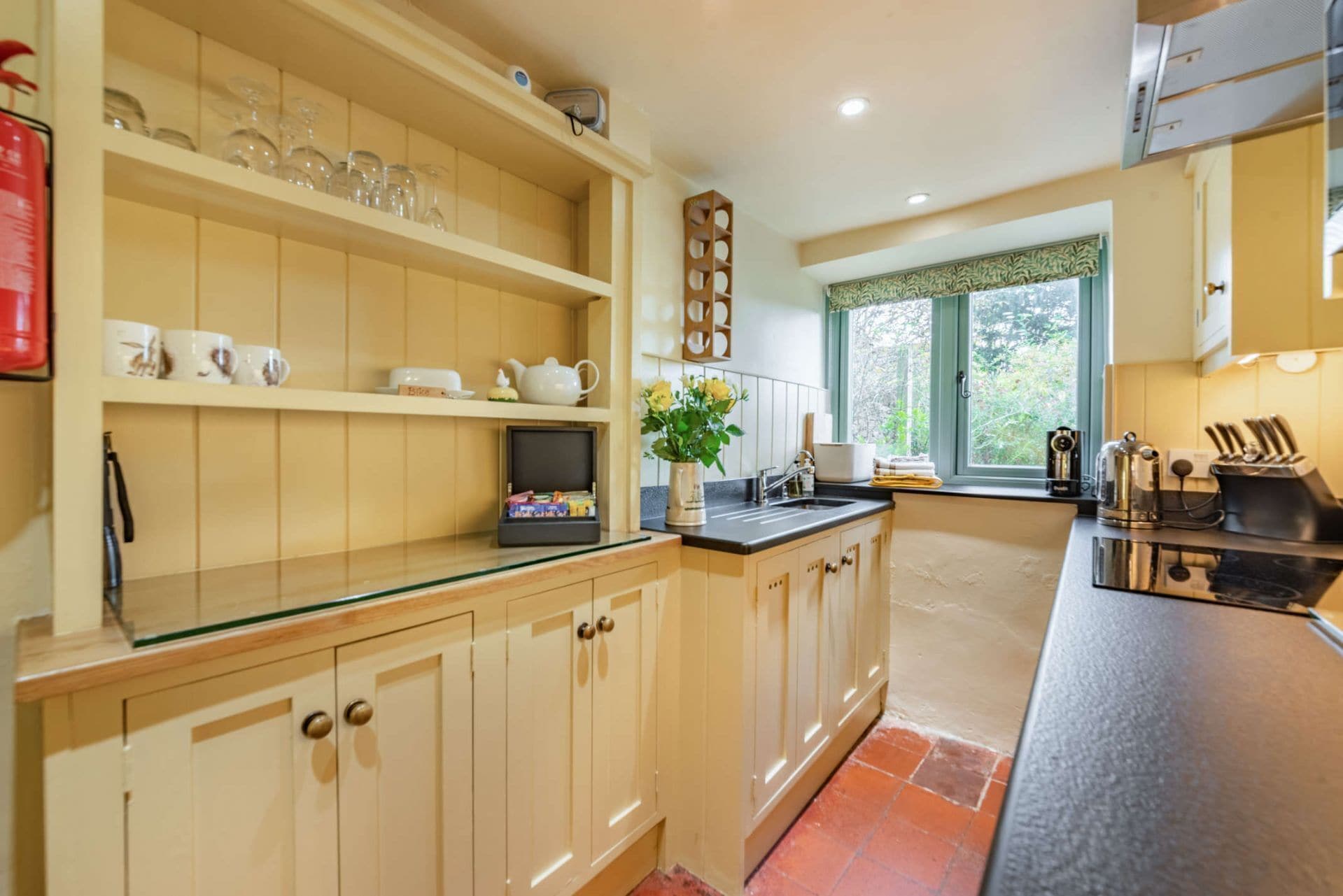 A kitchen with wooden cabinets, a glass countertop, a window with a view, and a stove.