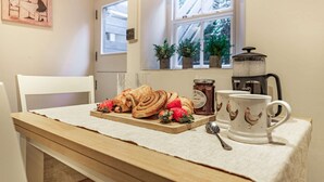 A breakfast setup with pastries and strawberries on a wooden table, a coffee pot, and a mug with a chicken design. - Dog friendly Cotswold cottage with a tranquil garden - Blenheim Cottage (Woodstock)