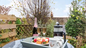 A picnic setup with a bottle of champagne, glasses, a tray with cupcakes and strawberries, and a coffee maker. - Dog friendly Cotswold cottage with a tranquil garden - Blenheim Cottage (Woodstock)