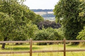 Proprietà recintata con vegetazione rigogliosa e vista su un paesaggio lontano.