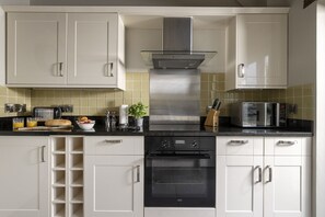 Una cucina moderna con mobili bianchi, una cappa in acciaio inossidabile, forno integrato e microonde.