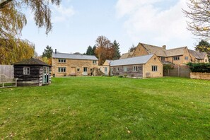 A stone farmhouse with a grassy yard and a small wooden structure.