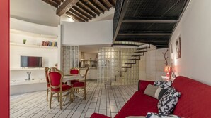 Ein modernes Interieur mit einem roten Sofa, einem Essbereich, einer Küche und einer Treppe.