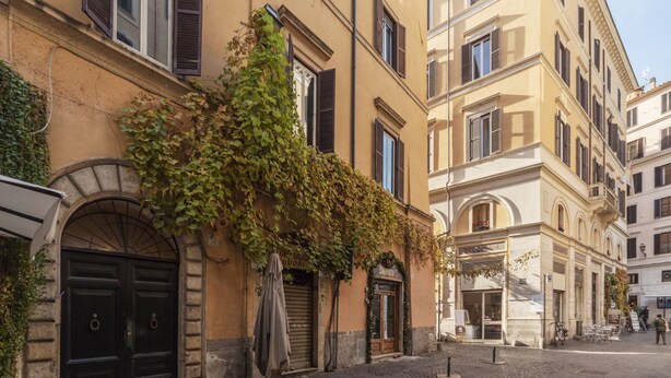 Eine Kopfsteinpflasterstraße mit Gebäuden, die Rundbogenportale und Fensterläden aufweisen.