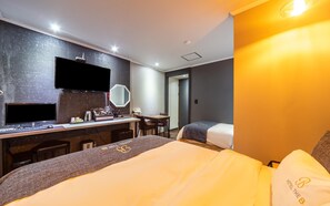 A hotel room with a bed, a desk with a computer, a mirror, and a small table. - Yeosu Hotel The B (Yeosu)
