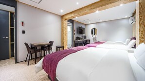 Ein Hotelzimmer mit zwei Betten, einem Schreibtisch und einem Fernseher.