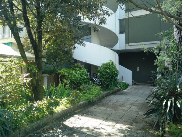 A modern building with a curved exterior and a paved pathway leading to a gated entrance.