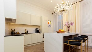 A modern kitchen with a central island, bar stools, and a chandelier.
