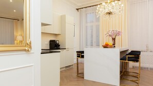 A modern kitchen with white cabinetry, a central island with stools, and a chandelier.