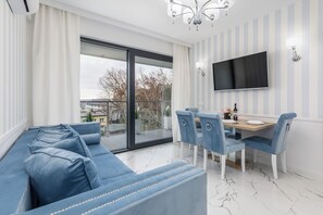 Un salon moderne comprenant un canapé, une table à manger, des chaises, un téléviseur et un balcon avec vue.