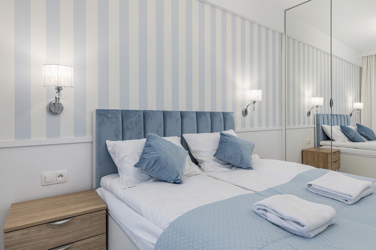 A hotel room with a large bed, two bedside tables, a nightstand, and a mirror.