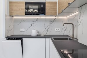 Une cuisine moderne équipée d’un four à micro-ondes encastré, d’une bouilloire et d’un évier.