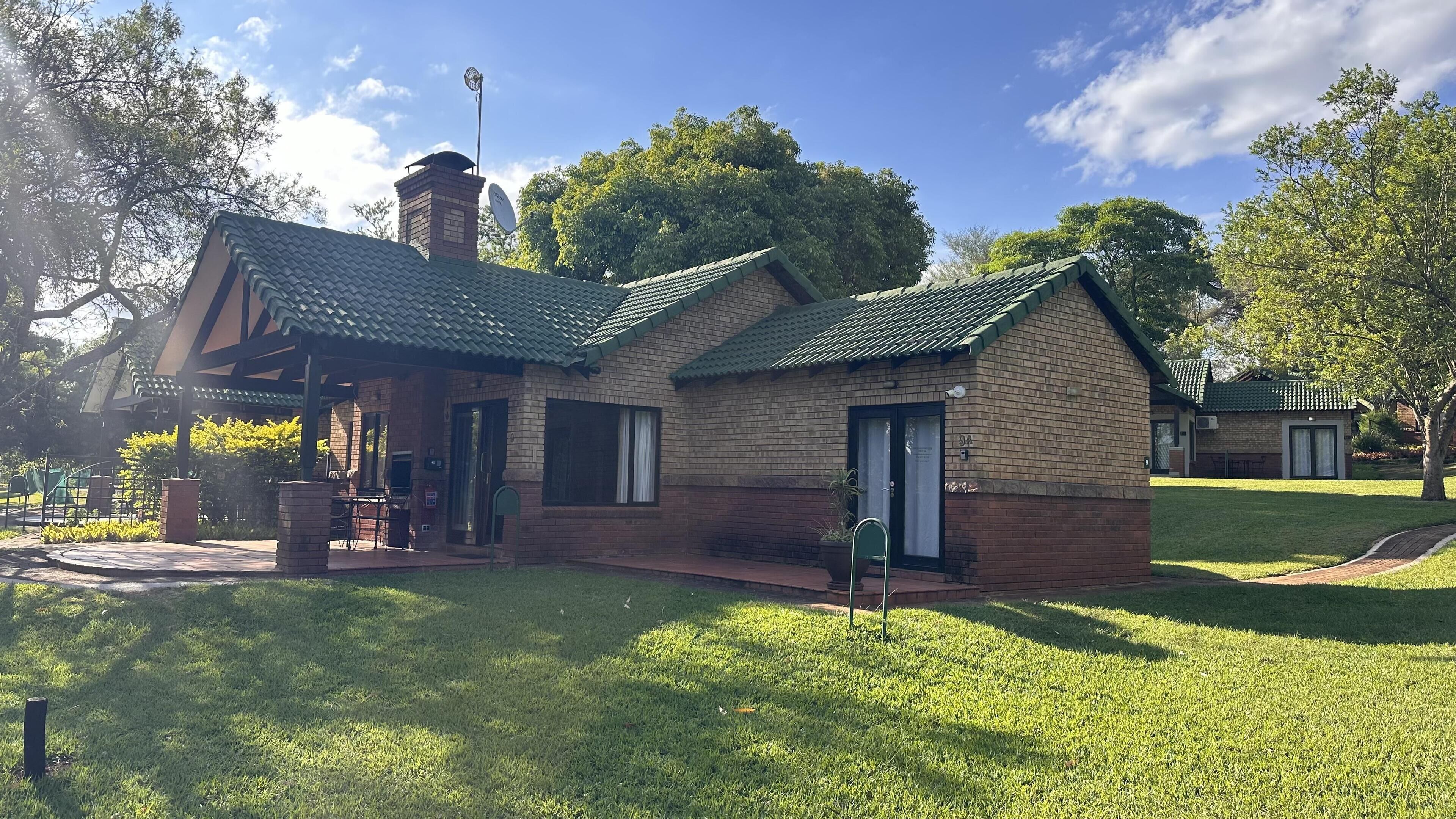 A small brick house with a green roof, a porch, and a well-maintained lawn.