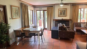A dining area with a table and chairs, a fireplace, and a sofa. - Greenway Woods Self Catering Unit no 9, Whiteriver (Mbombela)