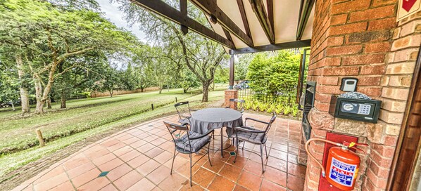 Un patio couvert avec un mur en briques, un extincteur et une table avec des chaises.
