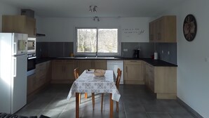 Una cocina compacta con una mesa de comedor, armarios de madera, una ventana y un reloj en la pared.