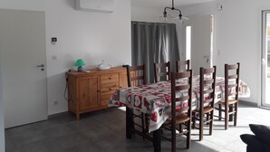 Comedor con una mesa dispuesta para cuatro personas, un aparador de madera y un aire acondicionado instalado en el techo.