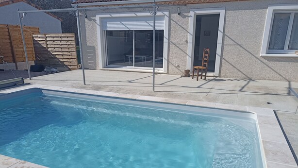Una piscina rectangular con agua azul cristalina, rodeada por una solana con baldosas.
