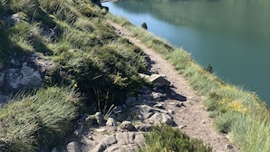 Una vista despejada de un lago rodeado de montañas y un sendero para excursionistas.