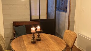 Una mesa de comedor redonda de madera con dos velas y un banco acolchado.