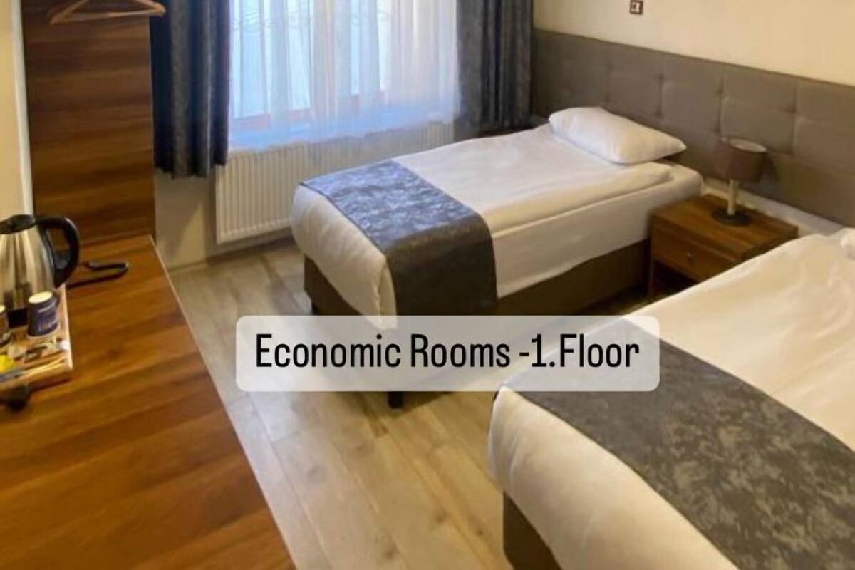 Quarto com cama, mesa de cabeceira e janela com cortinas.