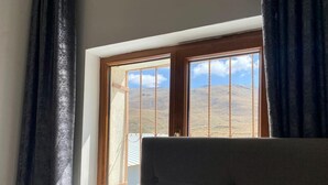 A room with a large window, curtains, and a view of a hilly landscape. - Zumrut Palas Hotel (Kayseri)