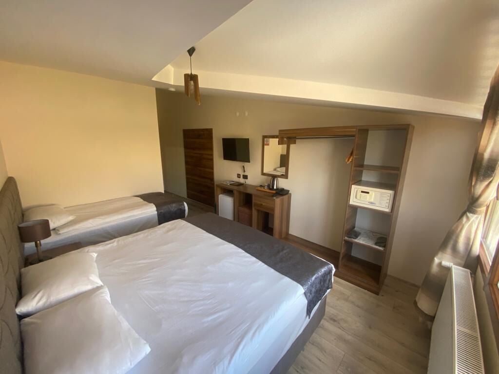 A hotel room with two beds, a desk, a mirror, a TV, and a wardrobe.