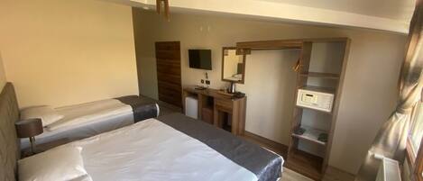 A hotel room with two beds, a desk, a mirror, a TV, and a wardrobe.
