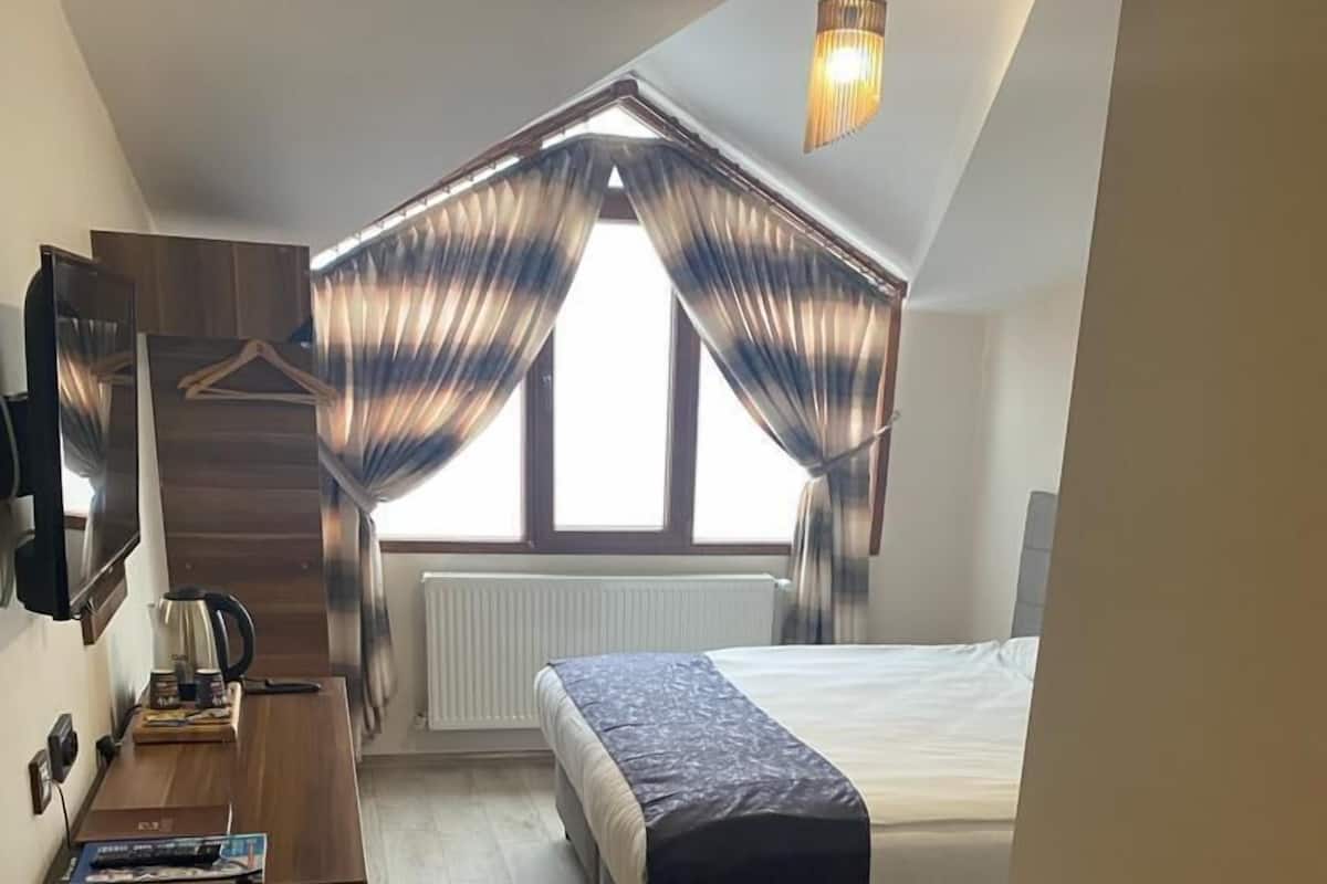 Quarto compacto com cama, escrivaninha e radiador.