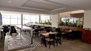 A modern restaurant with a buffet setup, multiple dining tables, and chairs. - Zumrut Palas Hotel (Kayseri)
