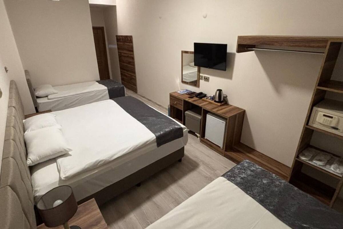 Quarto de hotel com duas camas, uma escrivaninha com computador, televisão e um mini frigorífico.