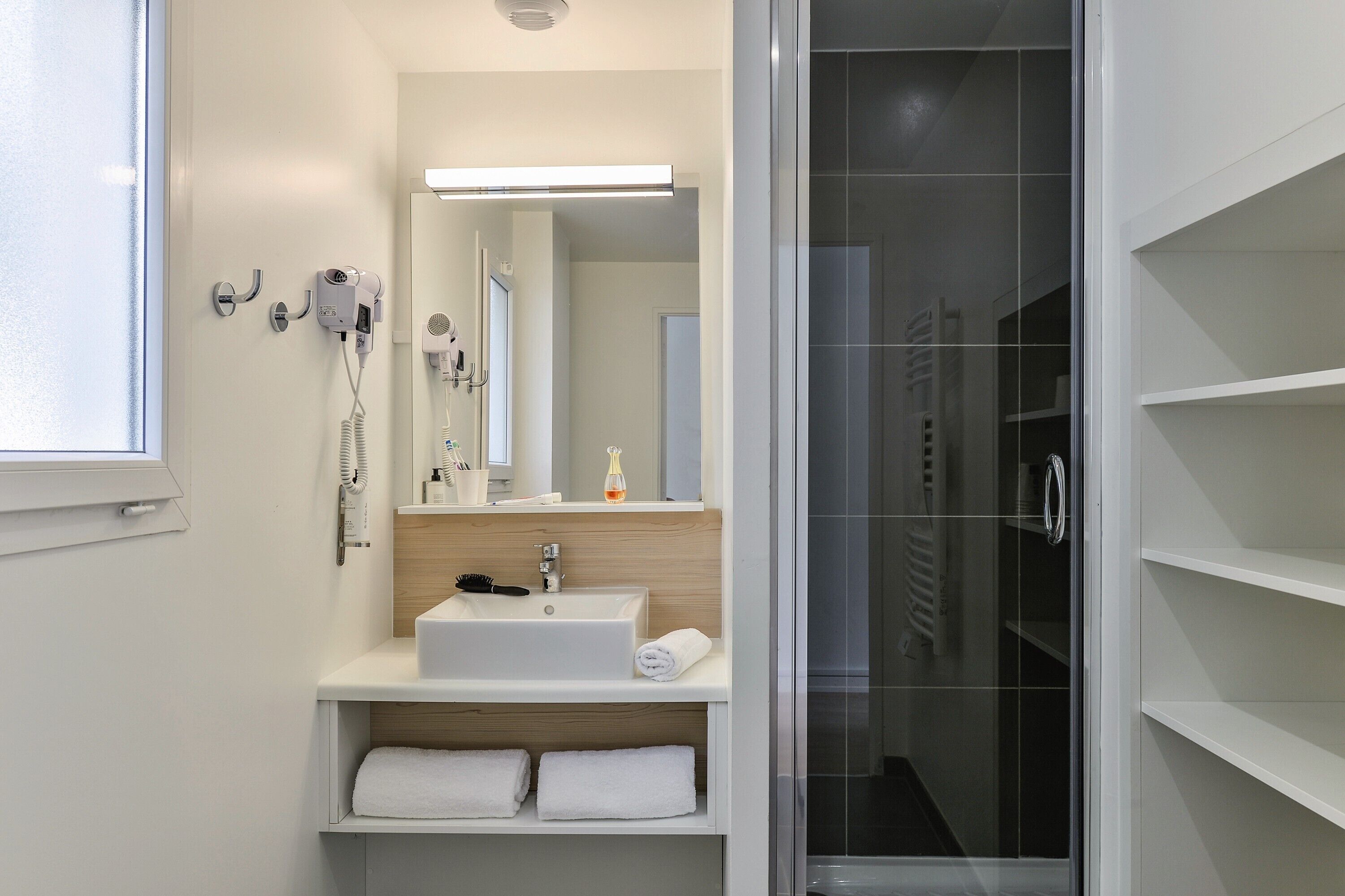 A modern bathroom with a white sink, mirror, and towel rack.