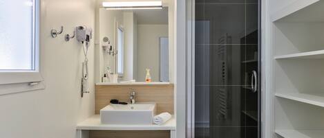 A modern bathroom with a white sink, mirror, and towel rack.