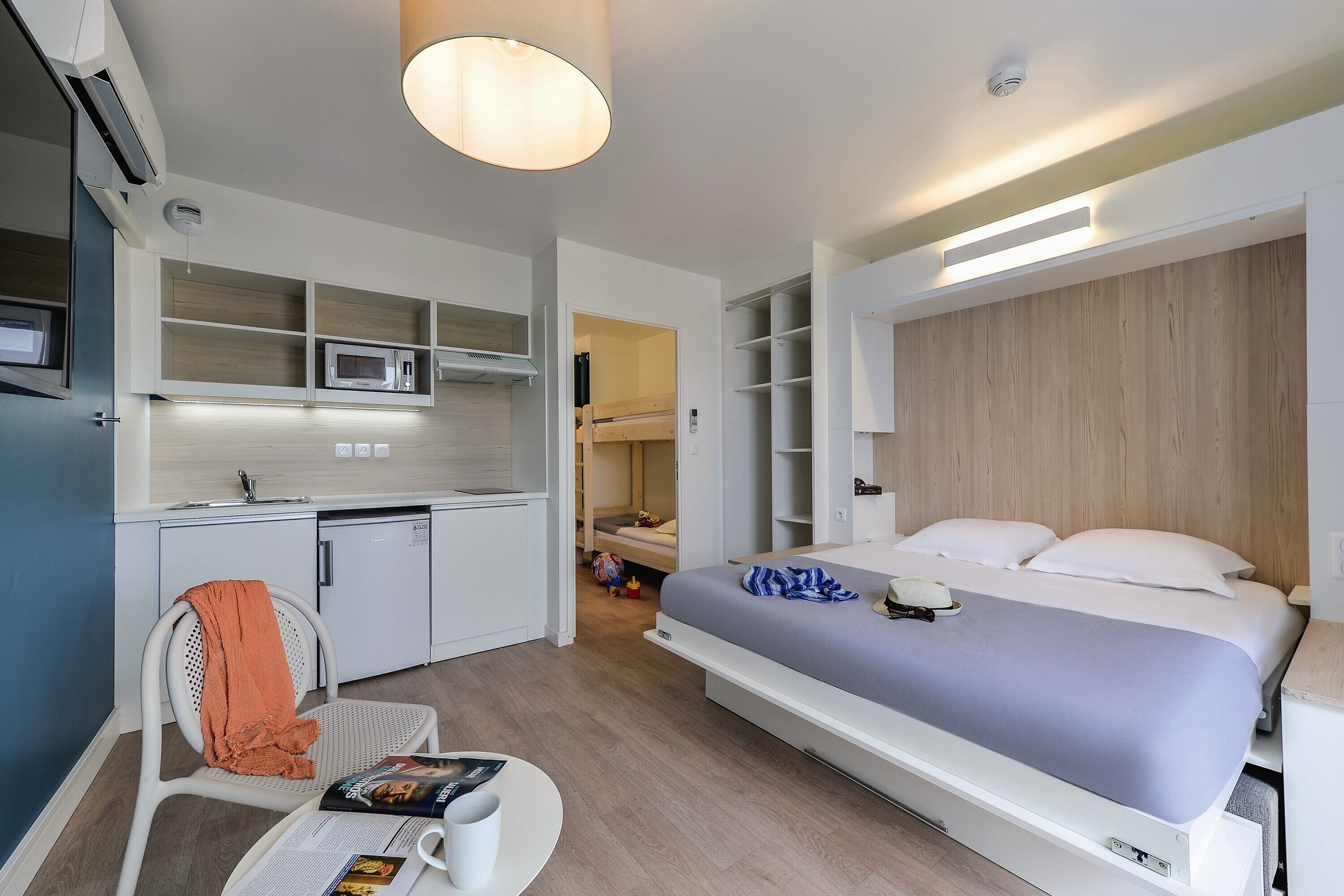 Ein kleines Hotelzimmer mit Bett, Küchenzeile und Sitzecke.