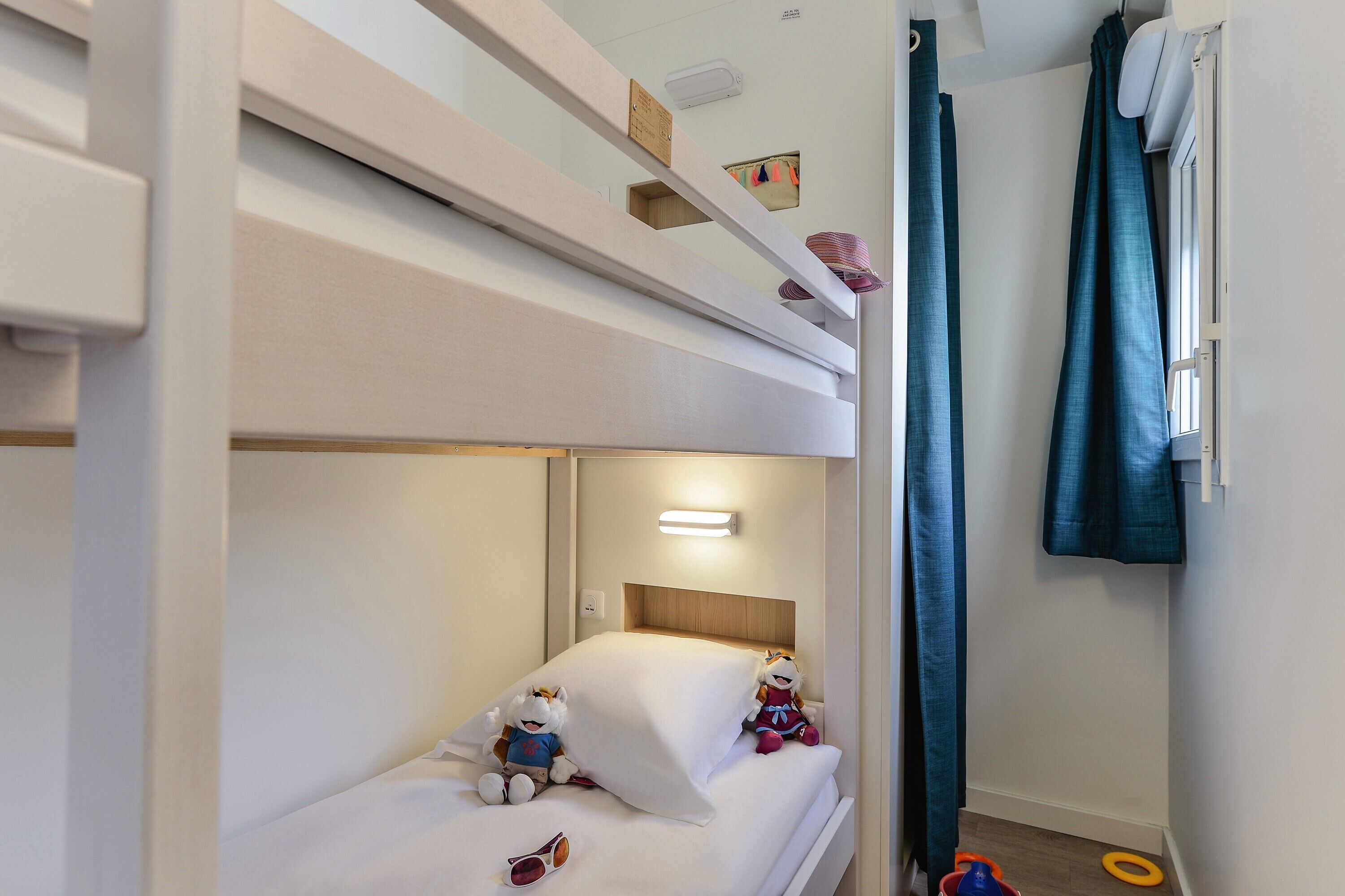 Habitación con literas, dos camas, luz nocturna y ventana con cortinas.