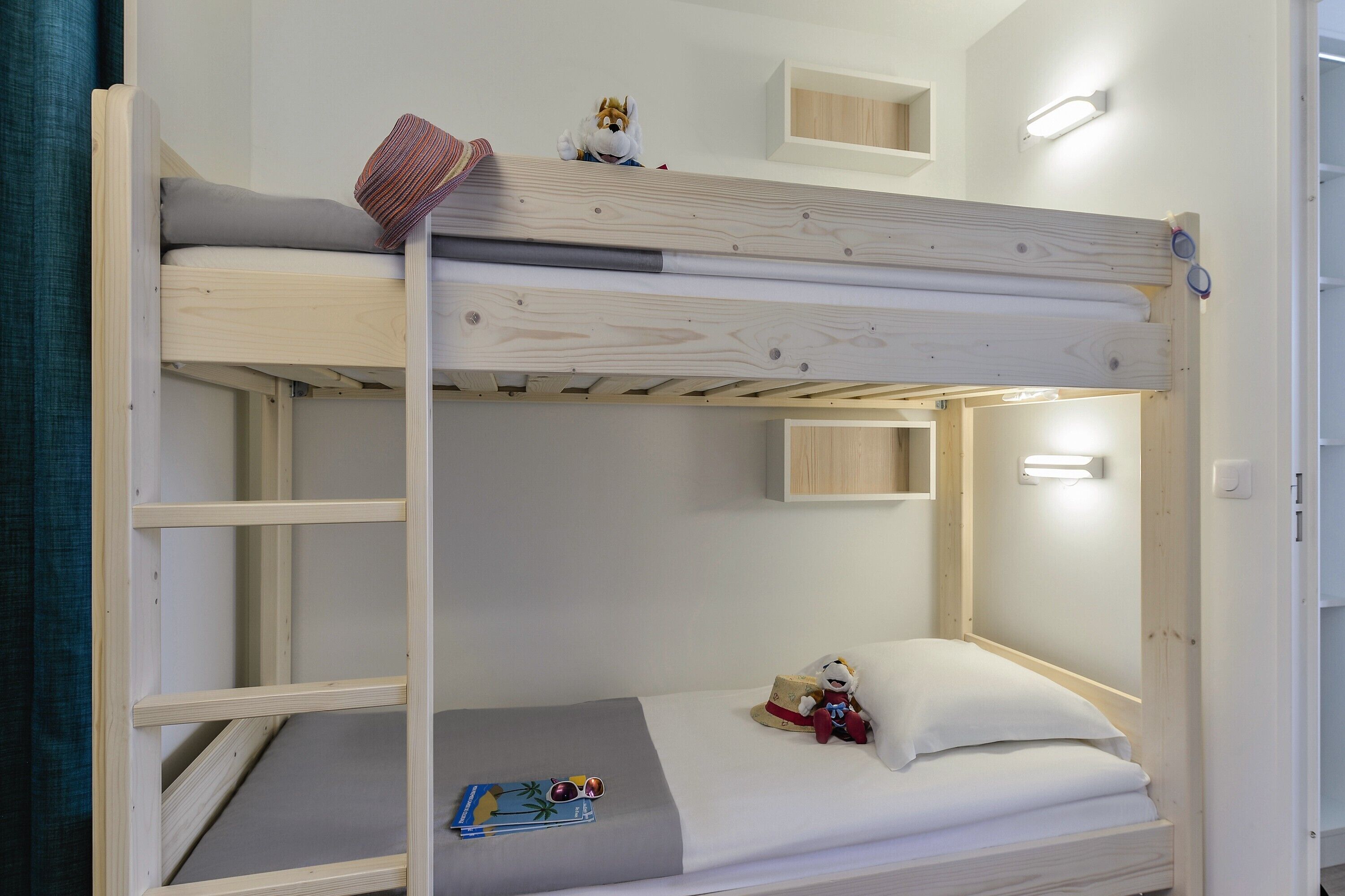 En våningssäng med en undre våningssäng, en liten hylla ovanför den undre våningssängen och en väggmonterad lampa.
