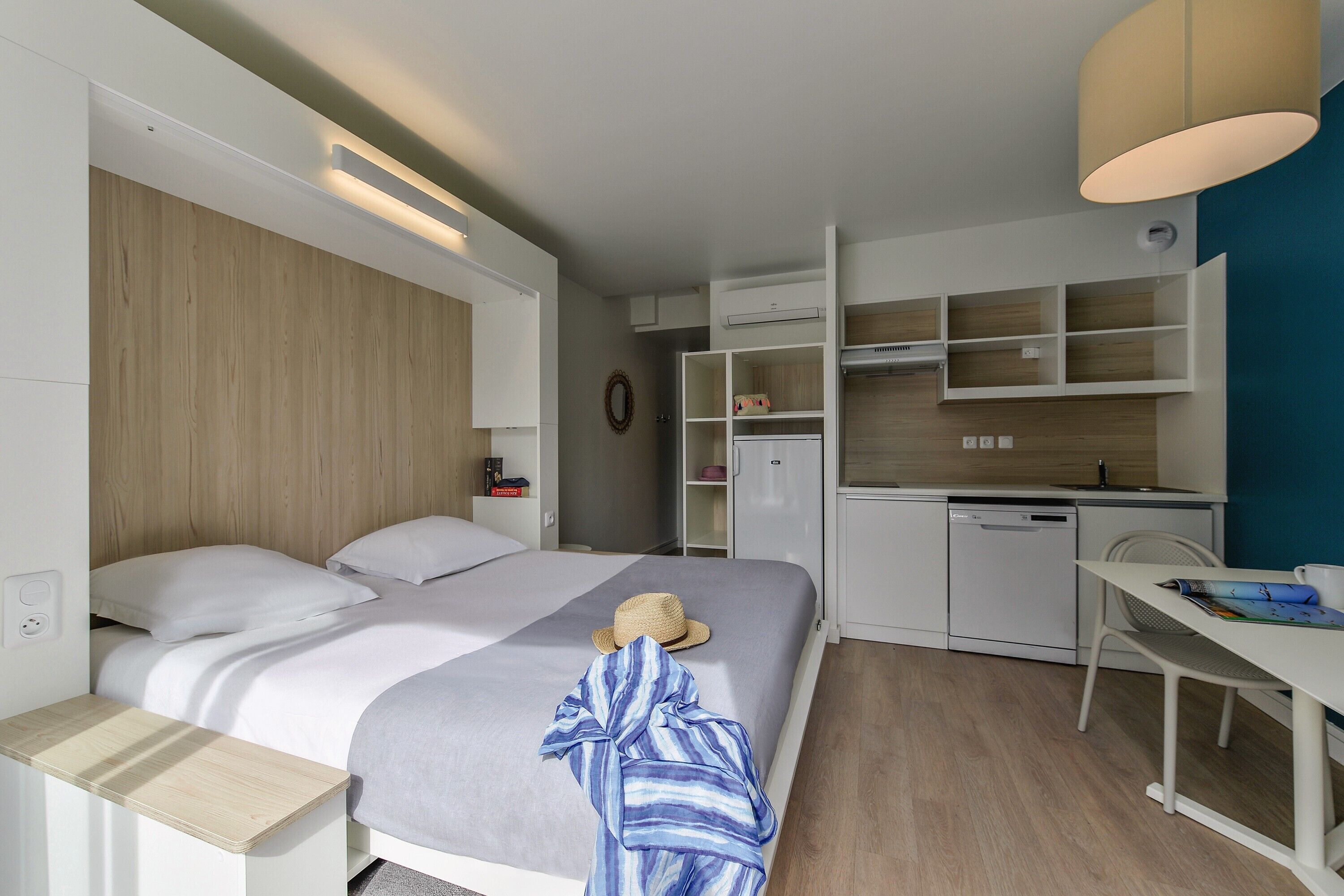 Une chambre d’hôtel moderne équipée d’un lit, d’un bureau, d’une kitchenette et d’une salle de bain.